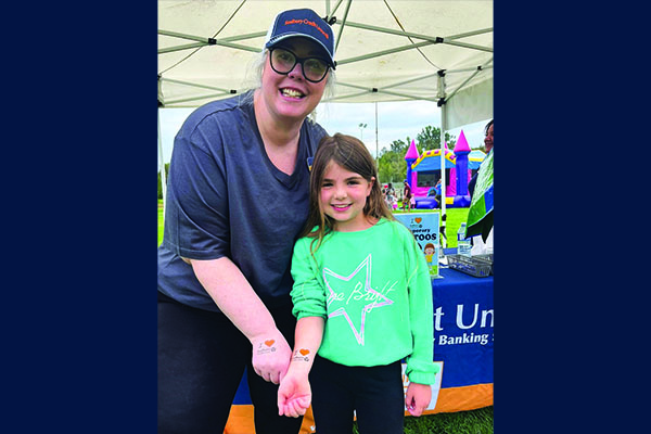 SCU staff member applies temporary tattoos at a community family event.