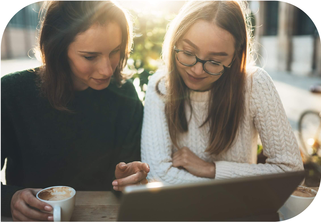 Two women working on laptop together.