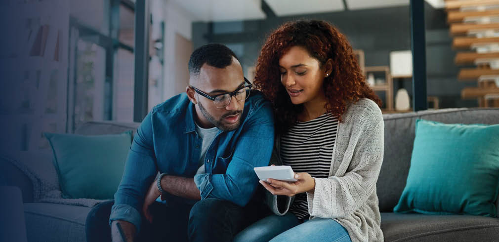 Couple looking at a device while sitting on a sofa.