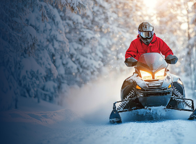 Snowmobile being driven through a forest.